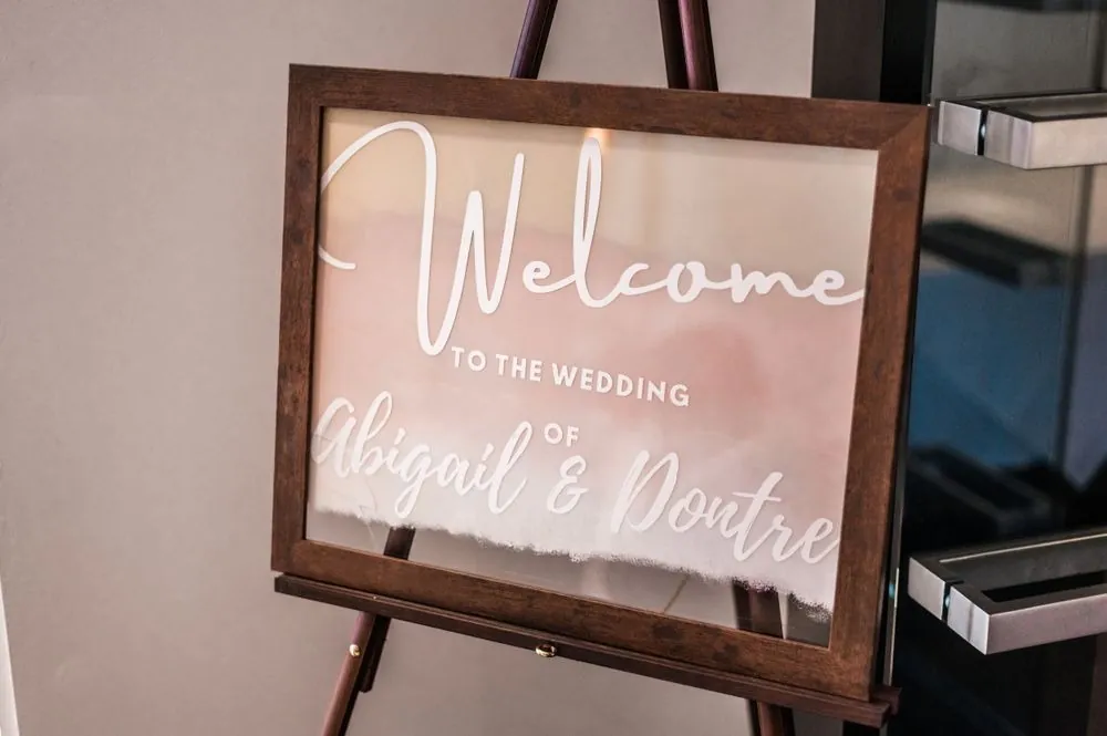 A welcome sign with the couple's names in white script on blush acrylic