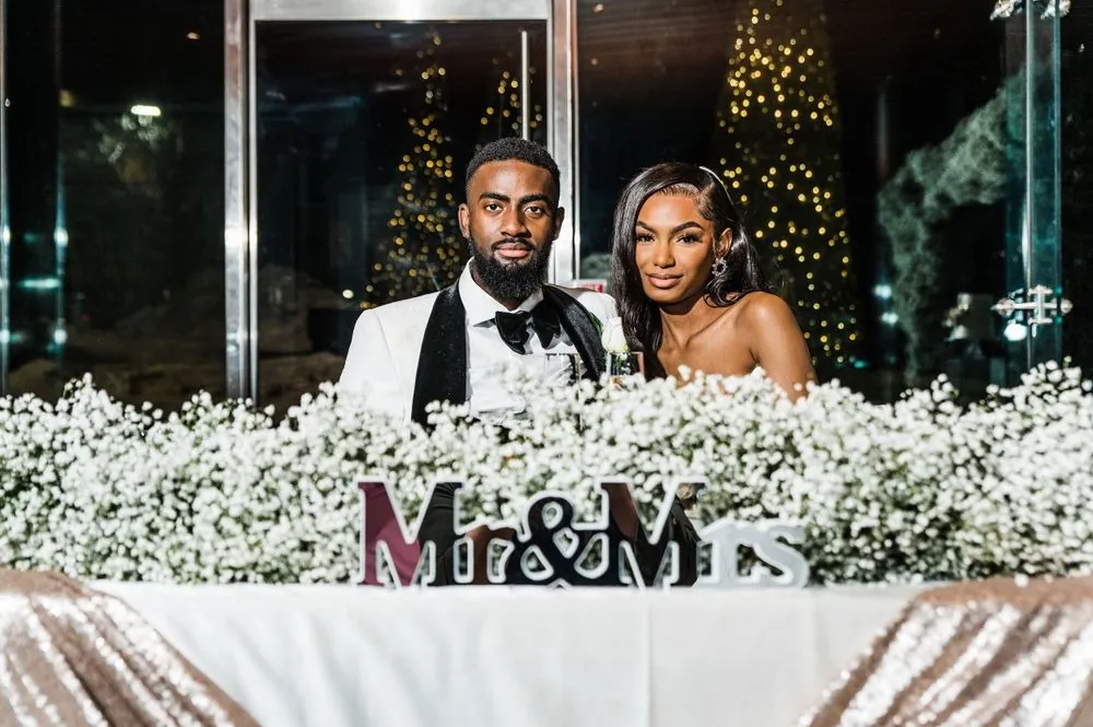 Abigail and Dontre sit behind a wall of baby's breath with a Mr and Mrs sign