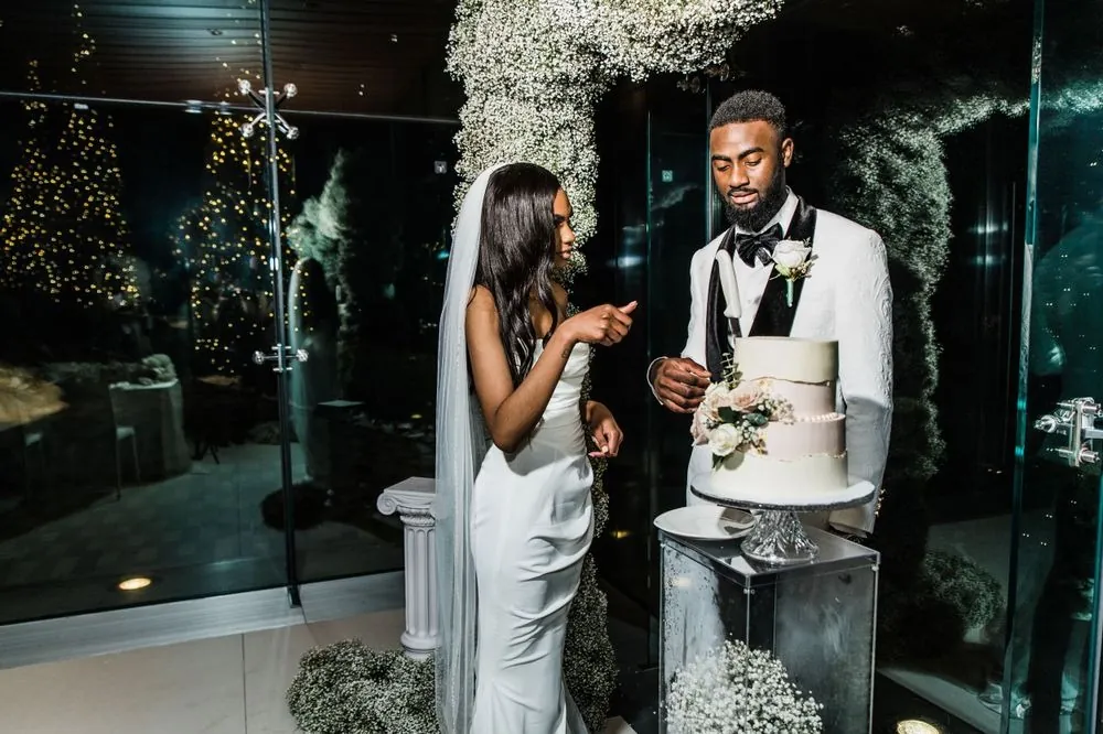 Abigail and Dontre cut their cake by the arch at night