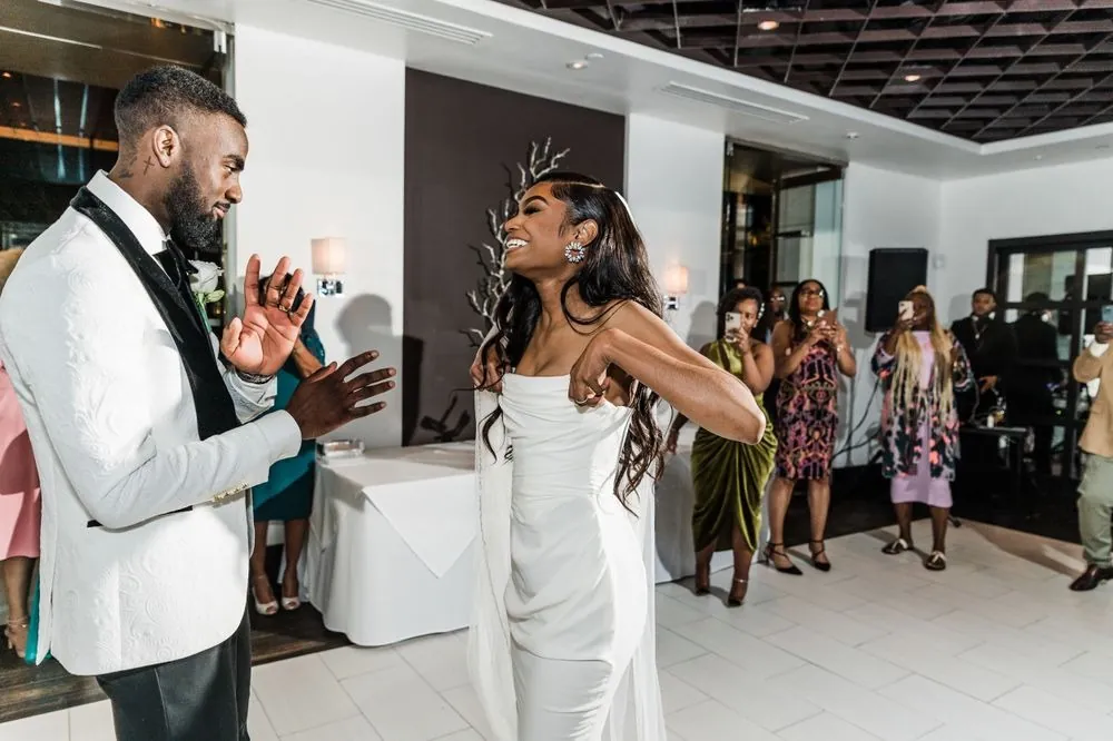 Dontre and Abigail dance face to face as guests clap along