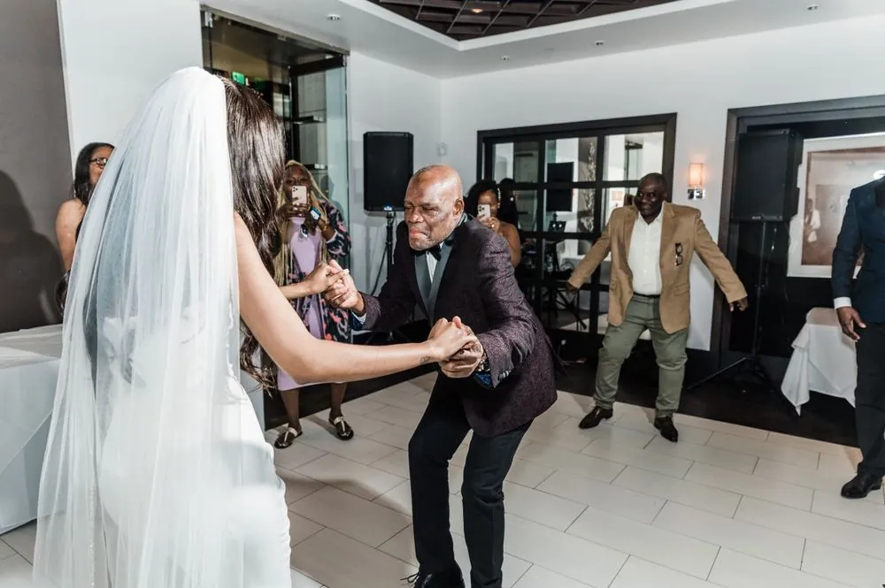 An older guest dips into a dance move with the bride as others join in