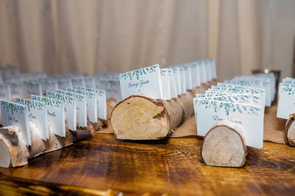 Escort cards tucked into rounds of sliced log on a rustic wood table