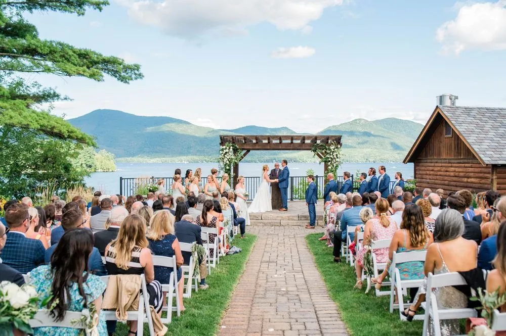 Guests fill the lawn as the couple stand under the pergola with mountains behind
