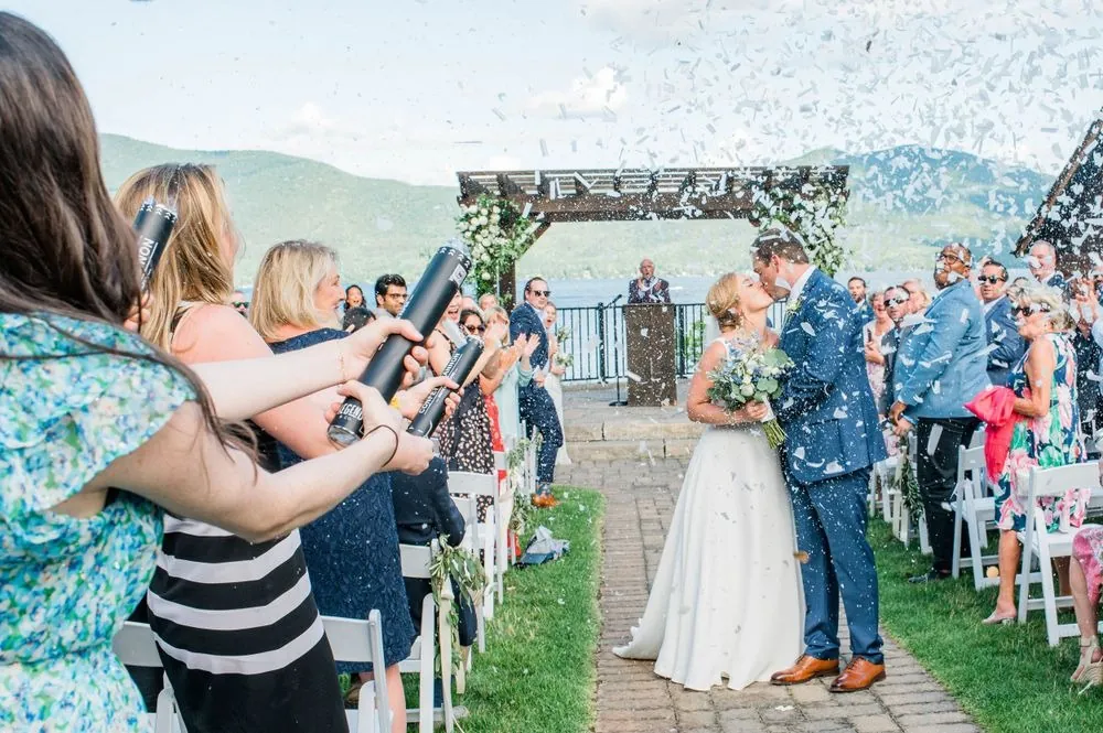 Guests fire confetti cannons as the couple kiss in the brick aisle