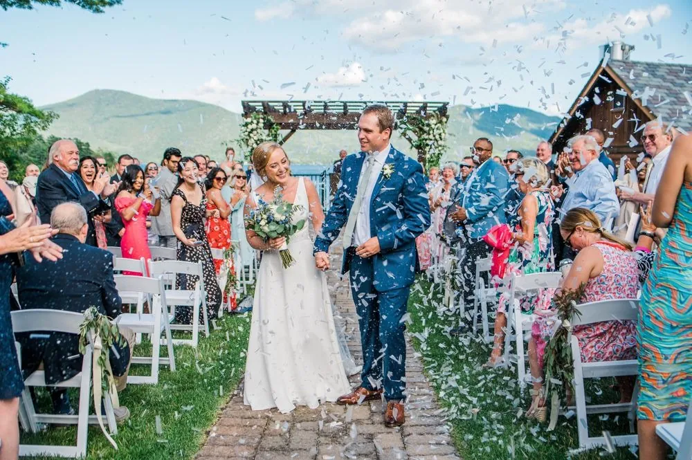 Alexandra and Robert walk back up the aisle through falling white confetti