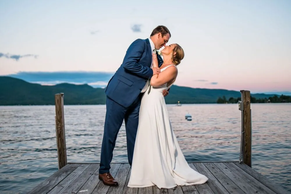 Robert kisses Alexandra on the dock as the sky turns pink over the mountains