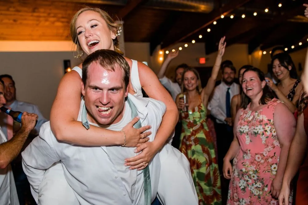 Robert carries a laughing Alexandra on his back under string lights
