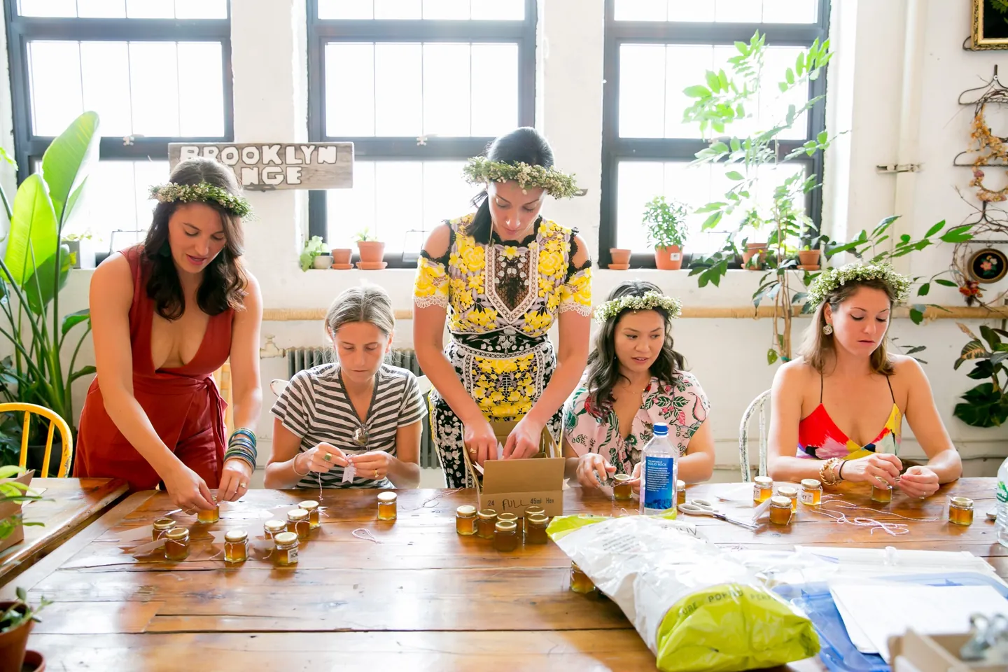 Friends gather around a long table covered in flowers in a bright loft room