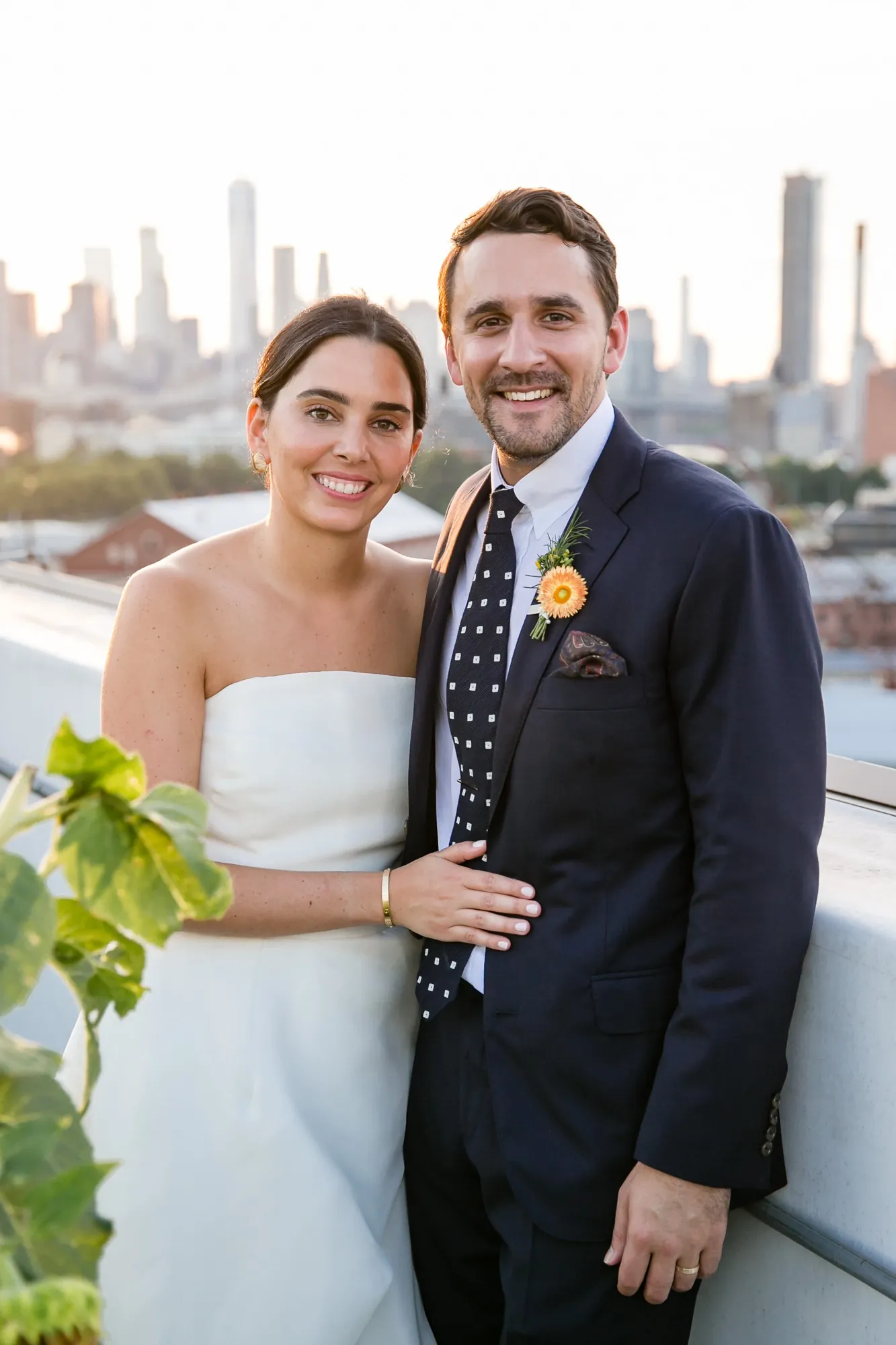 Alexis and David smile together on the rooftop with Manhattan towers in the distance