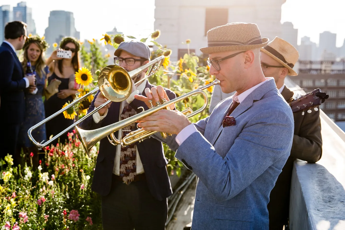 A brass band plays trombone and trumpet among sunflowers during cocktail hour