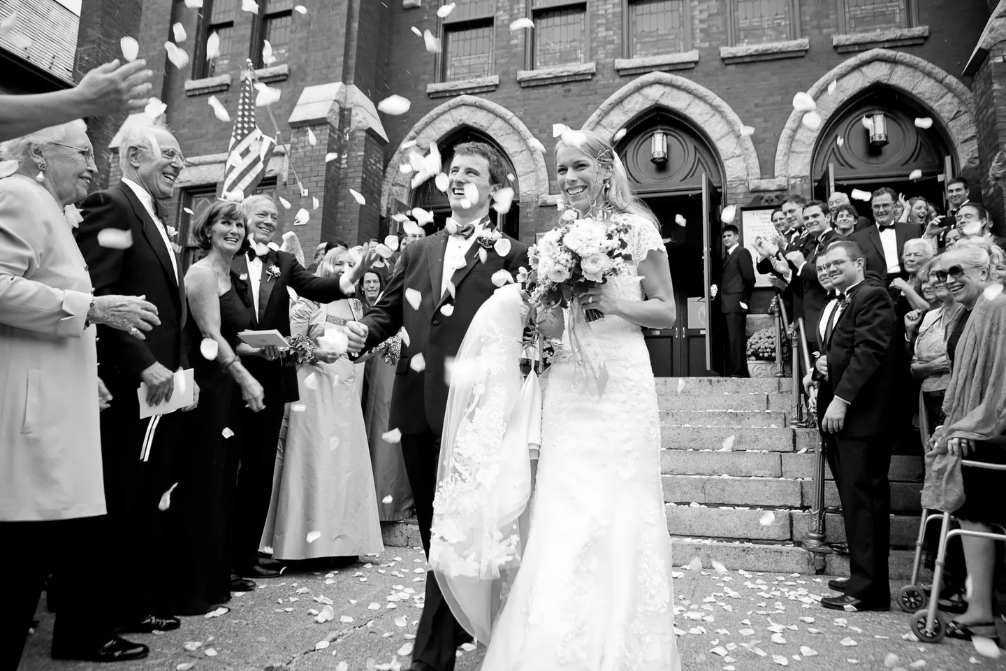 Alli and Dave leave the brick church laughing as guests throw white petals