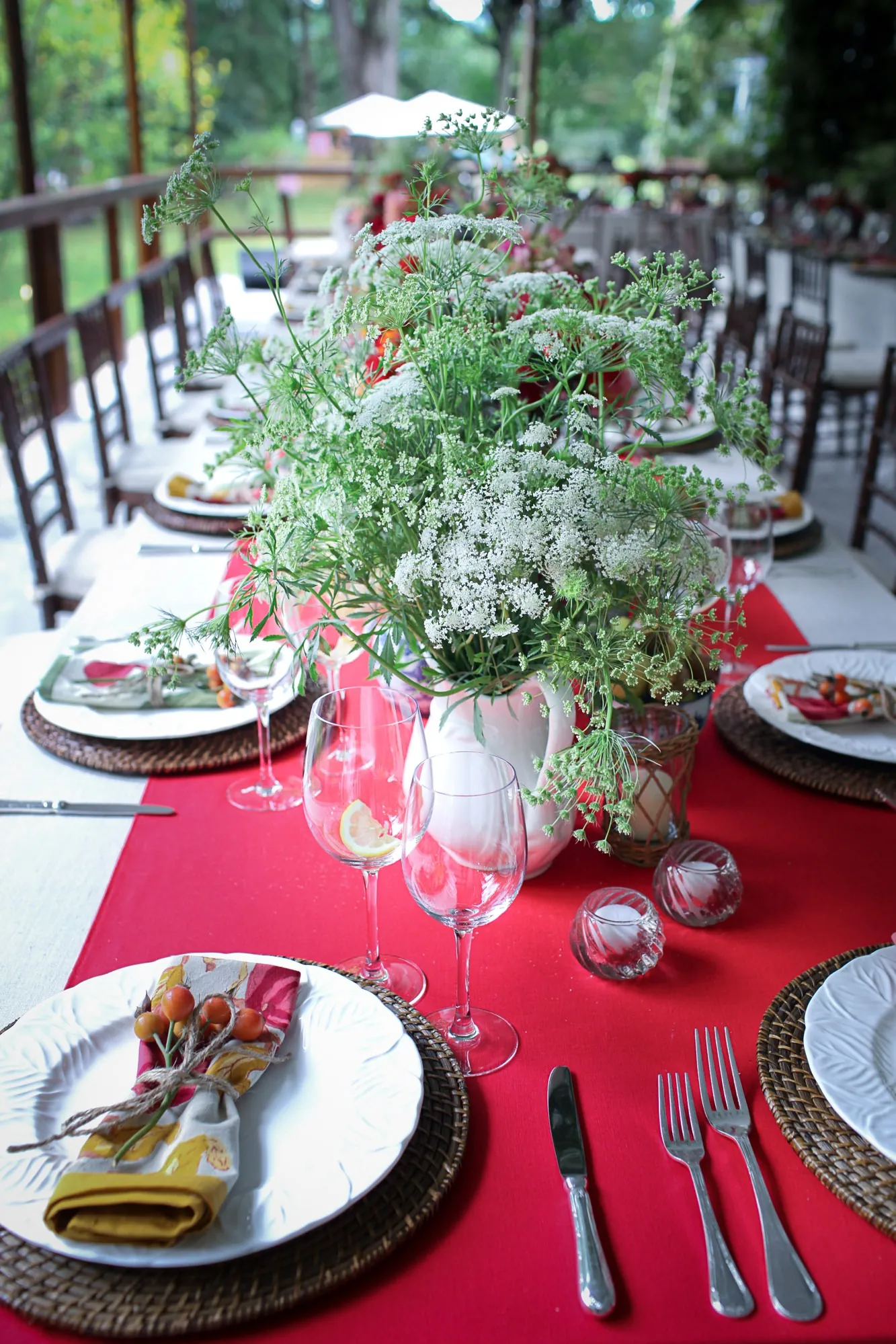 A long table set with red runners, greenery, and lantern light