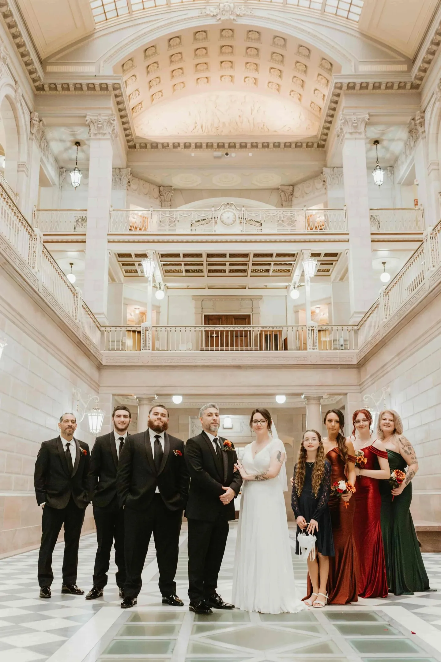 The wedding party lines up on the checkered marble floor of the atrium