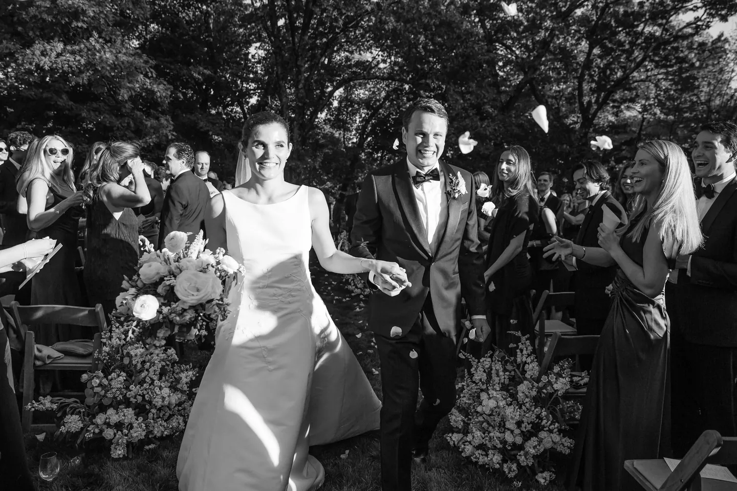Angie and Matt walk out through clapping guests, captured in black and white