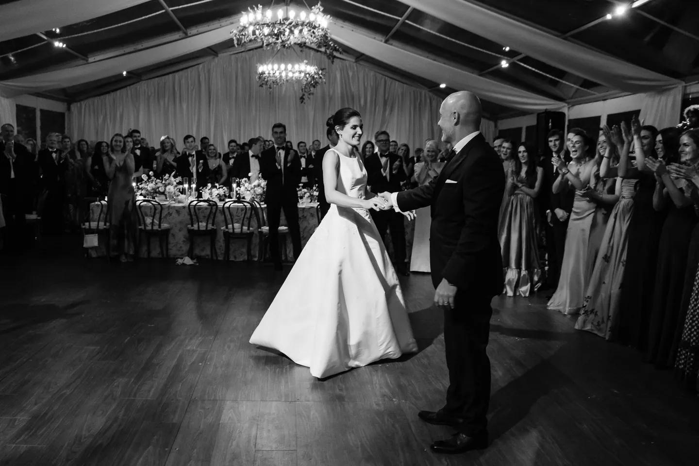 The first dance in black and white, guests pressed close around the floor