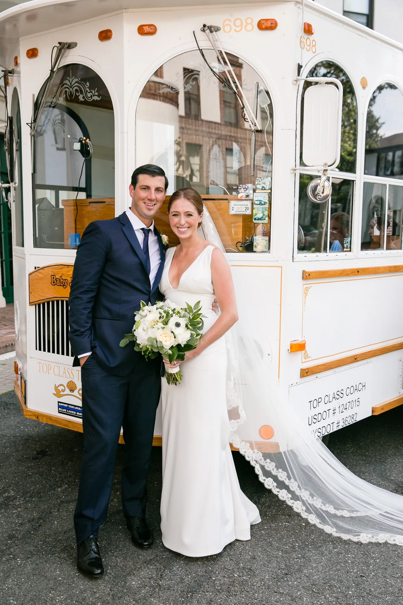 Anna and John stand at the back of a white trolley, her veil spilling out