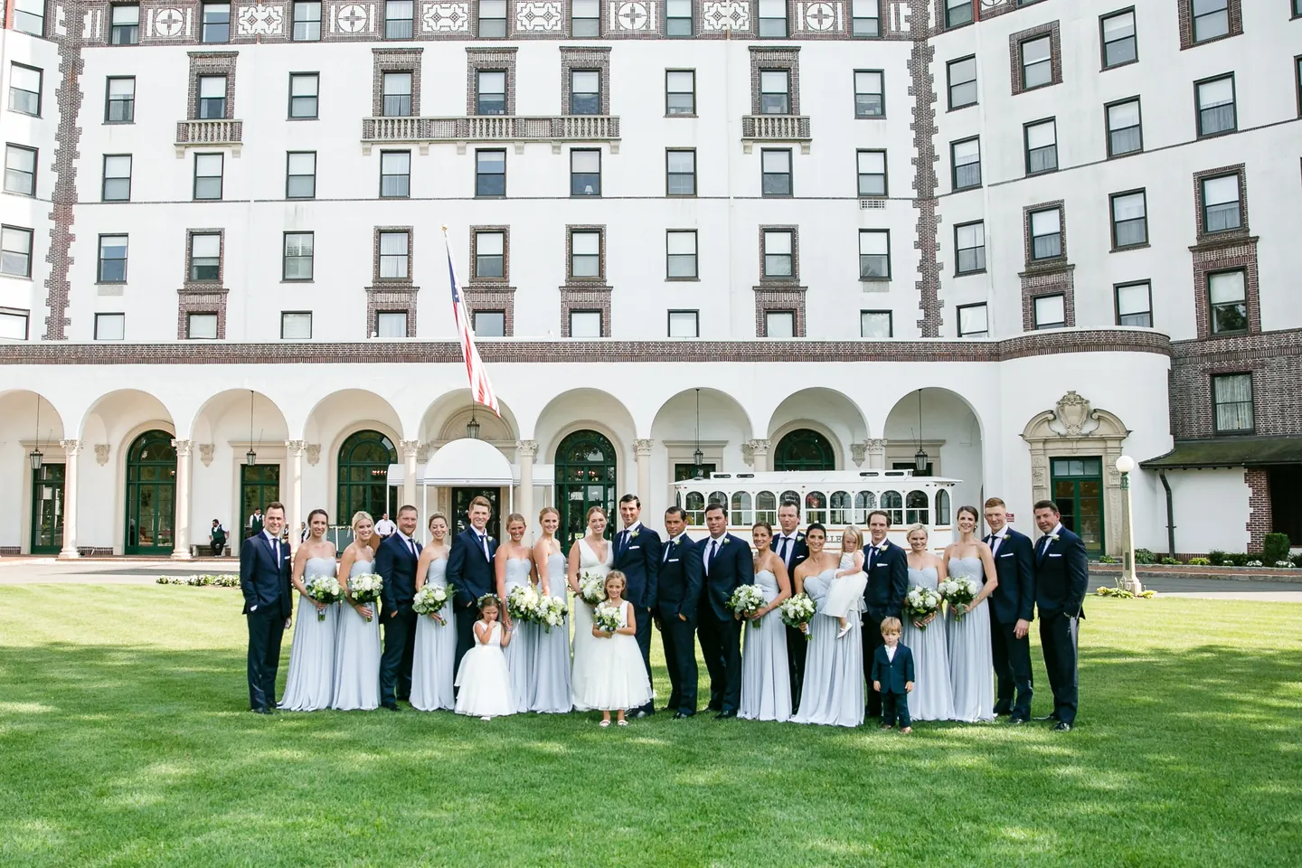 The full wedding party lines up on the lawn below the clubhouse colonnade