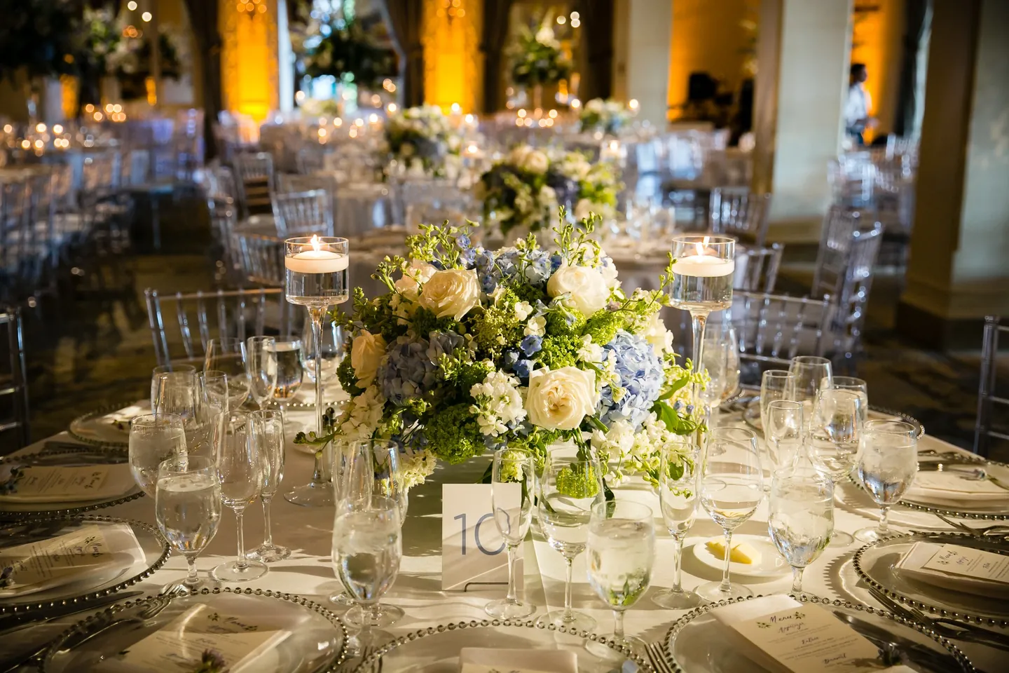 A low centerpiece of hydrangea and white roses among crystal glassware