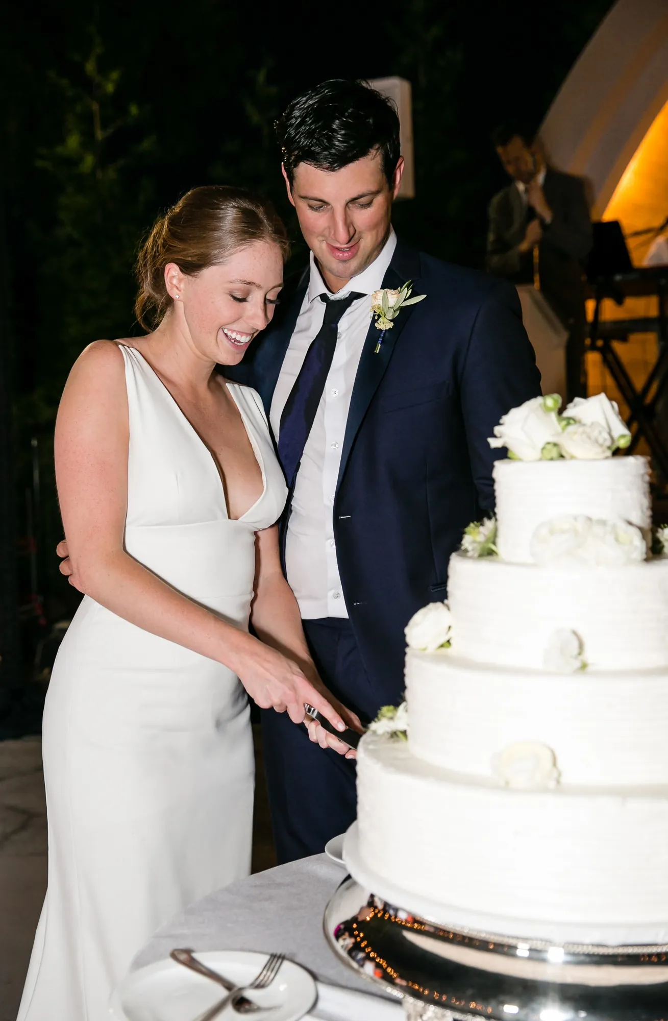 Anna and John cut a tiered white cake together in the ballroom
