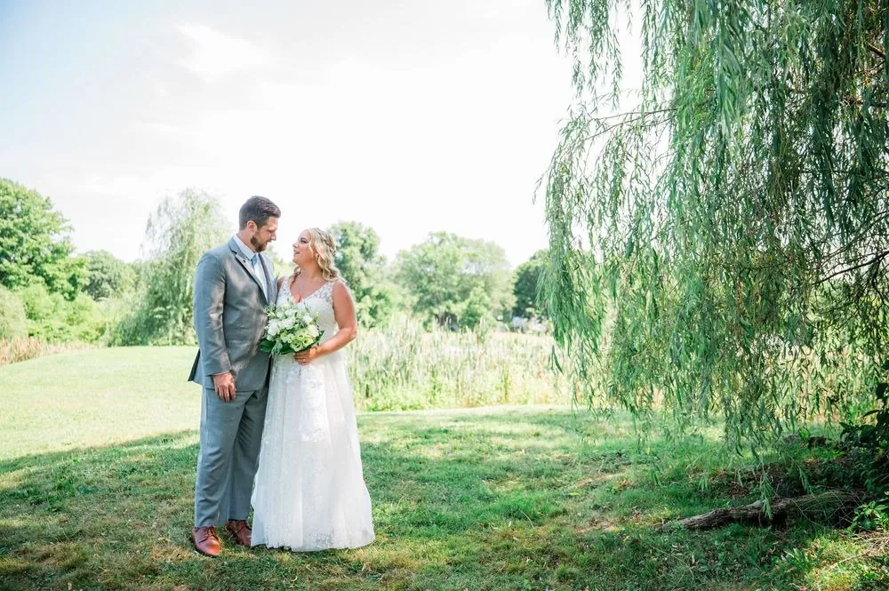 Arianne and Michael look at each other beneath the hanging branches of a weeping willow