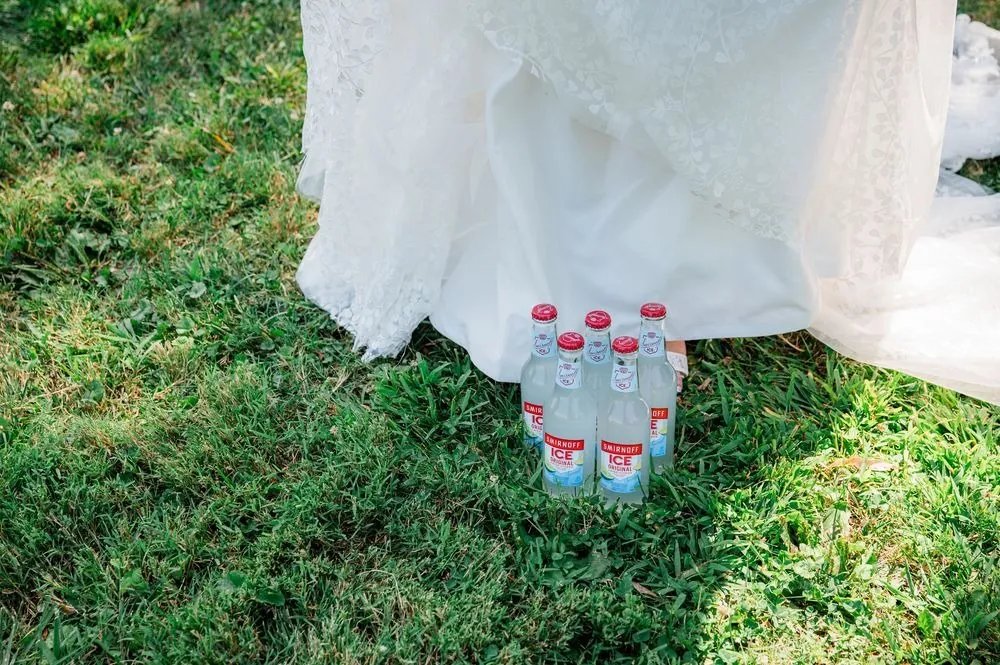 Small bottles hidden in the grass beneath the hem of the bride's lace gown