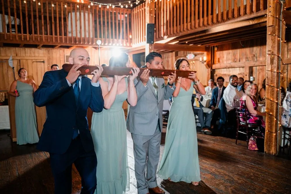 Wedding party members tip back a shot ski together as they enter the barn