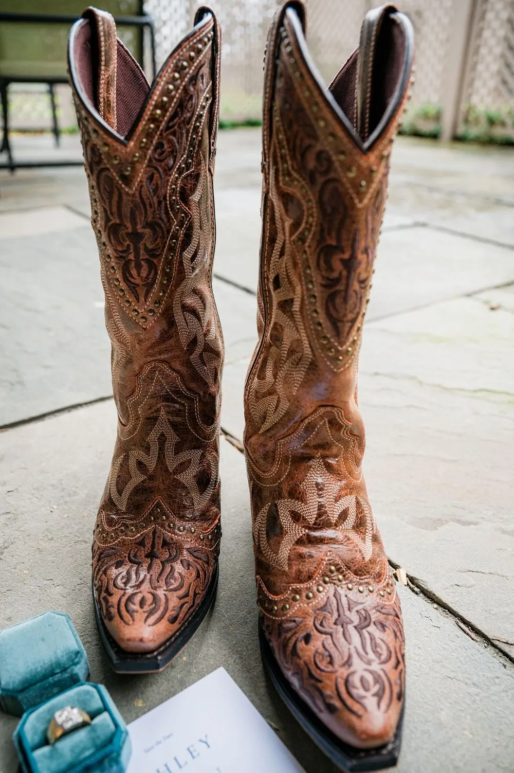 The groom's tooled brown leather cowboy boots standing on a hotel carpet