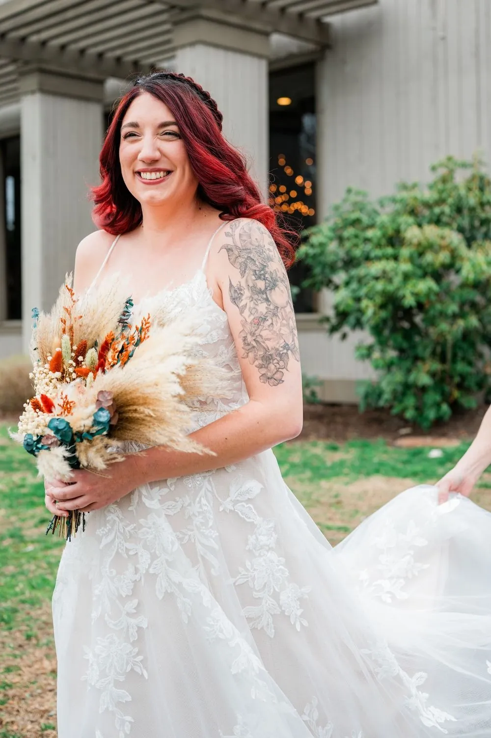 The bride holds her dried-flower bouquet outside the hotel, smiling over her shoulder