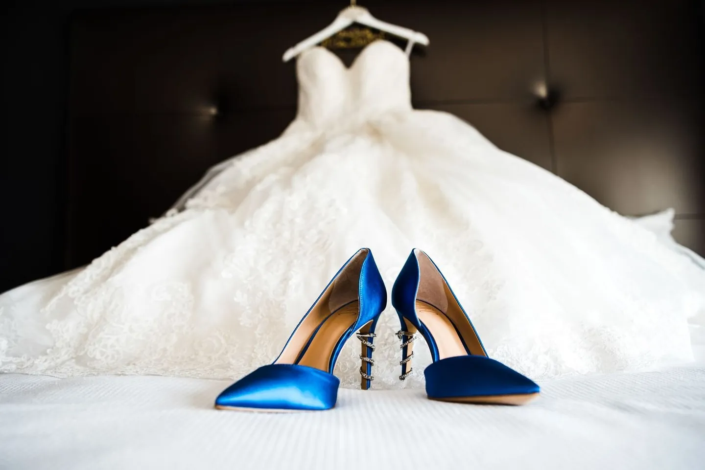 Royal blue heels rest on the full lace skirt of the wedding gown