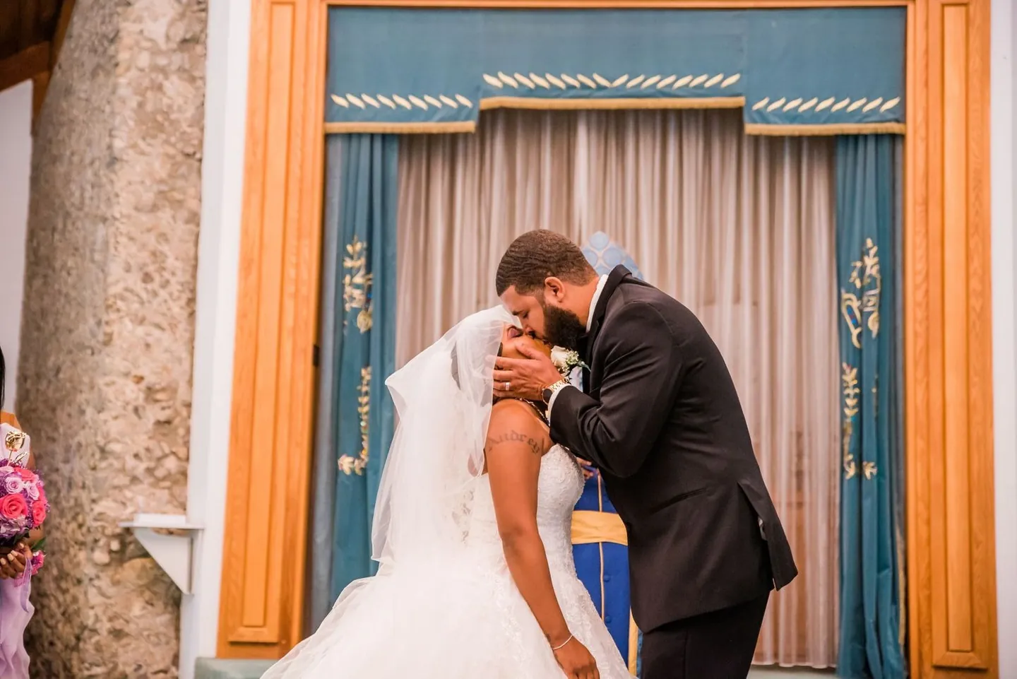 Darren kisses Ashley before a blue velvet curtain at the front of the church