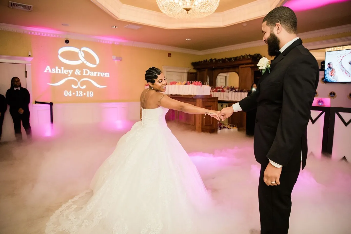 Ashley and Darren begin their first dance in low fog under a projected monogram