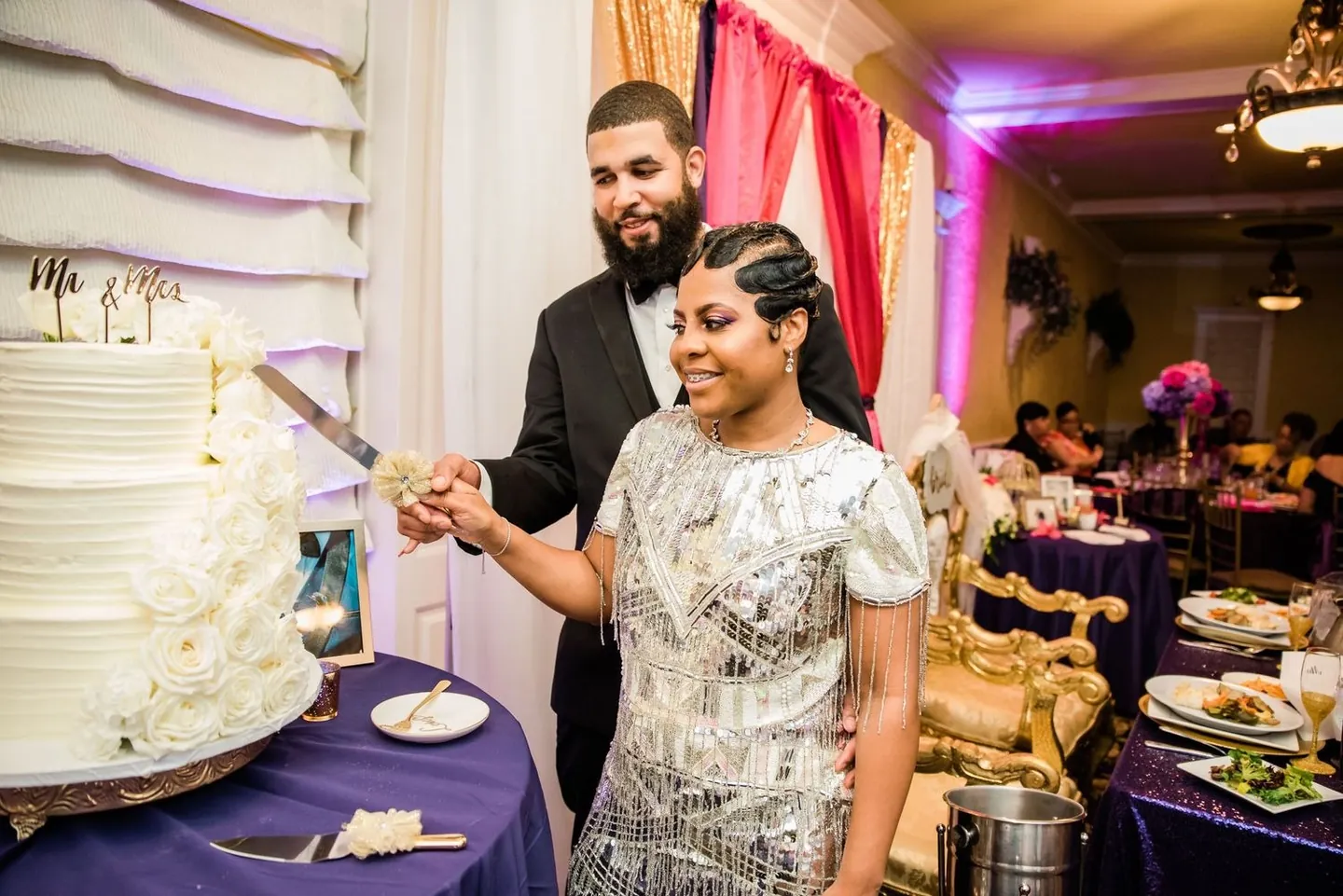 Ashley in a silver fringe dress cuts the white cake with Darren