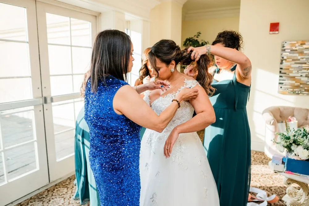 Family members help the bride into her gown by the windows