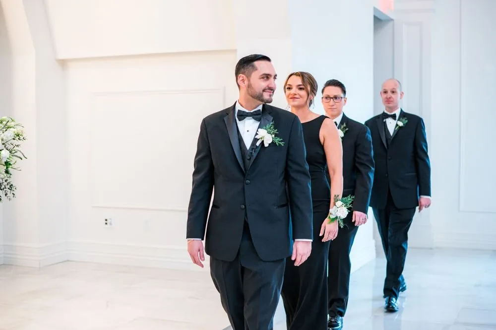 The groom walks with his groomsmen through a bright white hall
