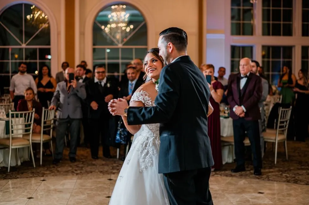 The couple shares their first dance as guests watch from the edge of the floor