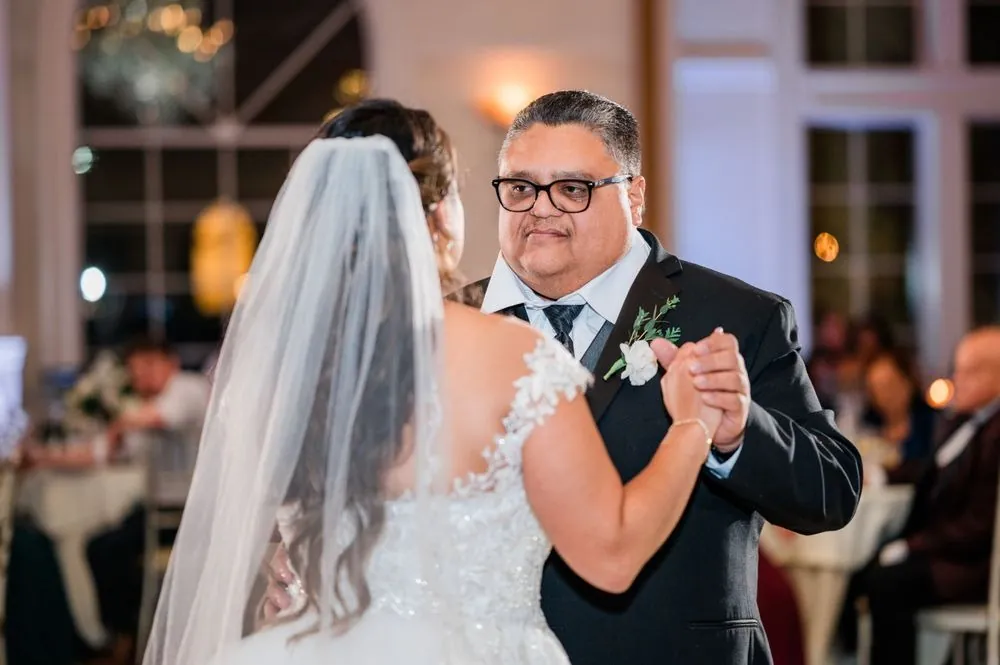 The bride dances with her father, her veil falling over her shoulder