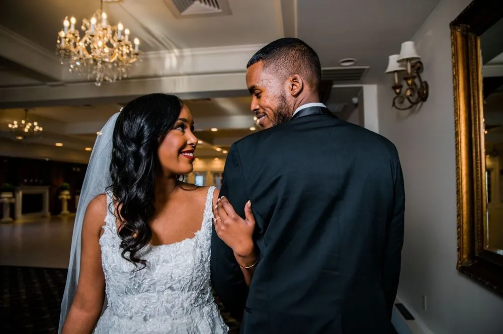 The groom turns to see the bride during their first look in the ballroom
