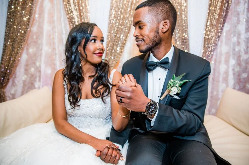The couple laughs together on the sofa, hands clasped