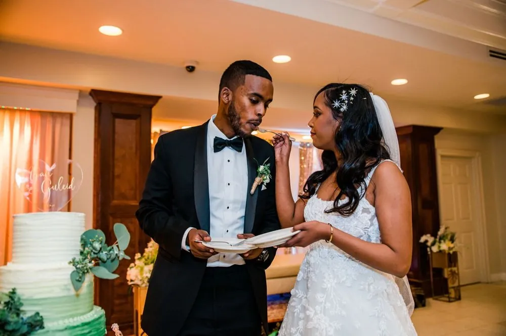 The bride and groom cut the green cake together under warm lights