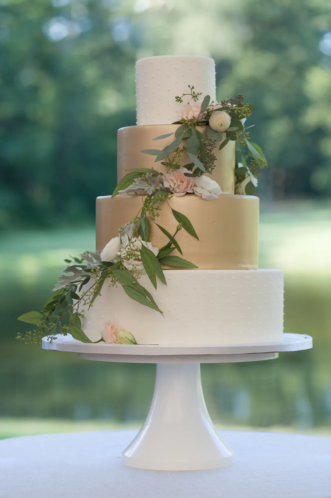 A tiered white cake trimmed with trailing greenery and blush flowers