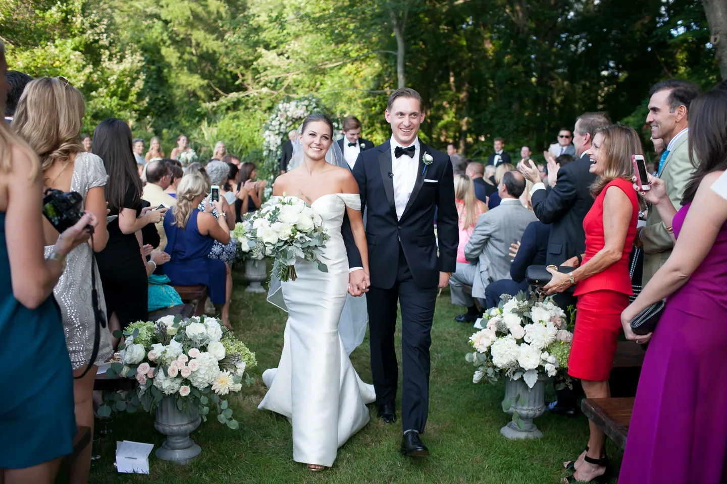 Becca and James walk back up the aisle as guests cheer on both sides