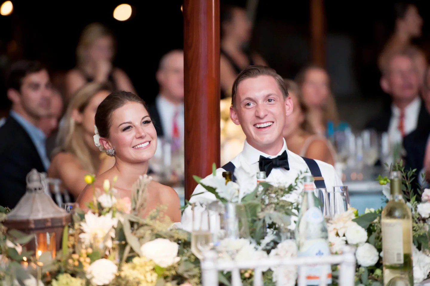 Becca and James laugh during the toasts at a candlelit table