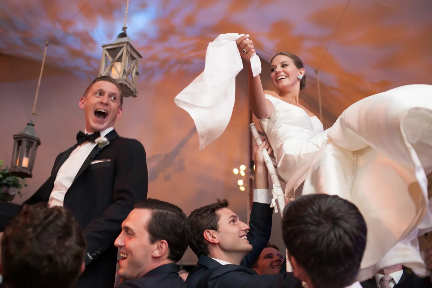 Becca and James are lifted high on chairs above a cheering crowd
