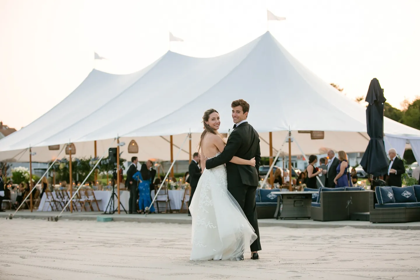 Britt and Andrew pause on the sand in front of the sailcloth tent as guests gather inside