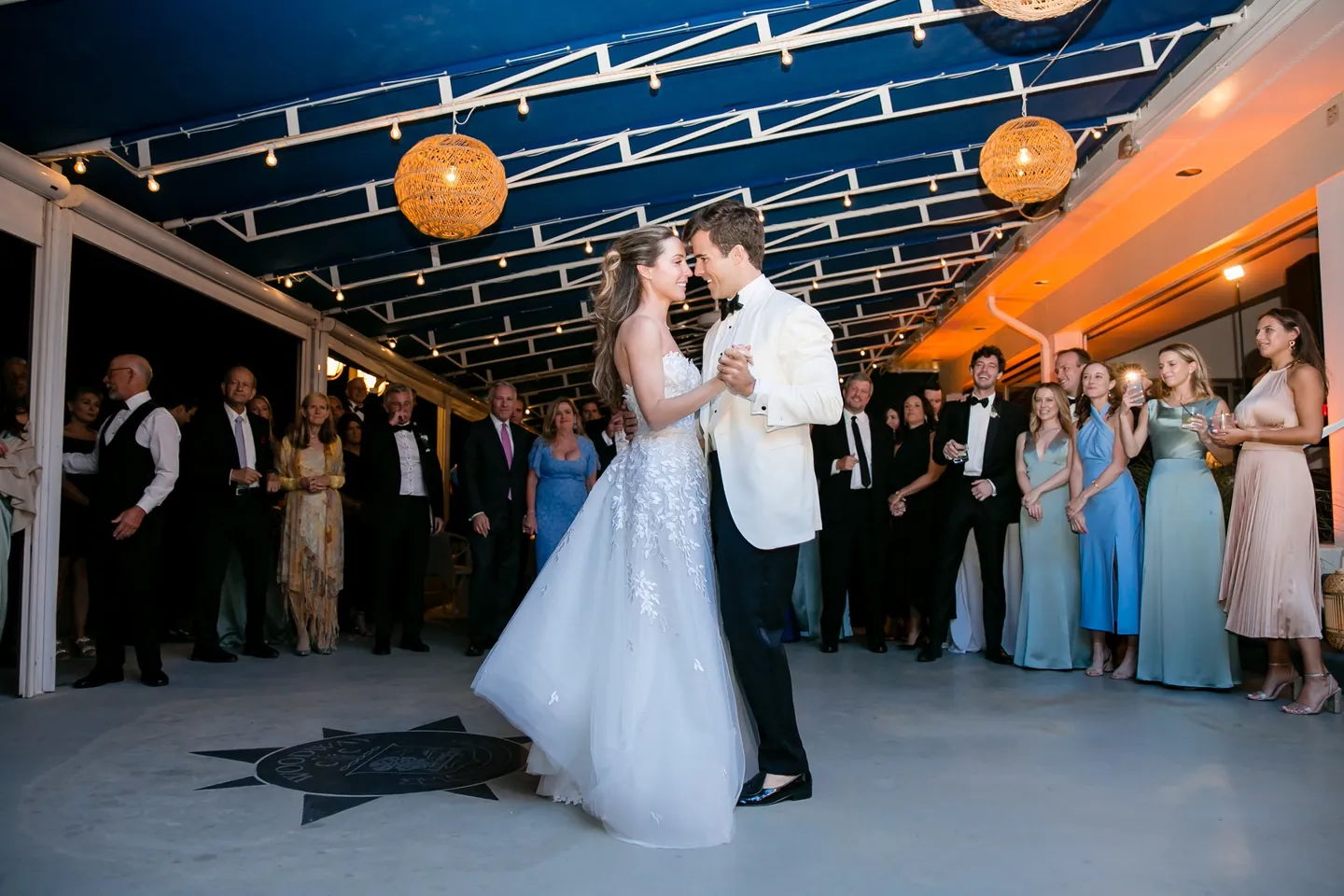 Britt and Andrew share their first dance under orange lanterns as guests look on