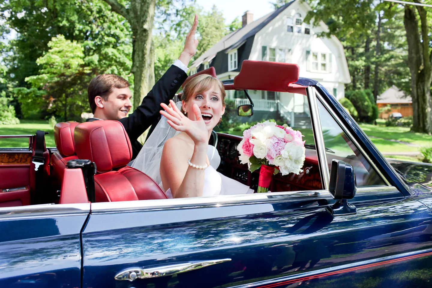Caity waves from a vintage convertible with red leather seats as Matt drives
