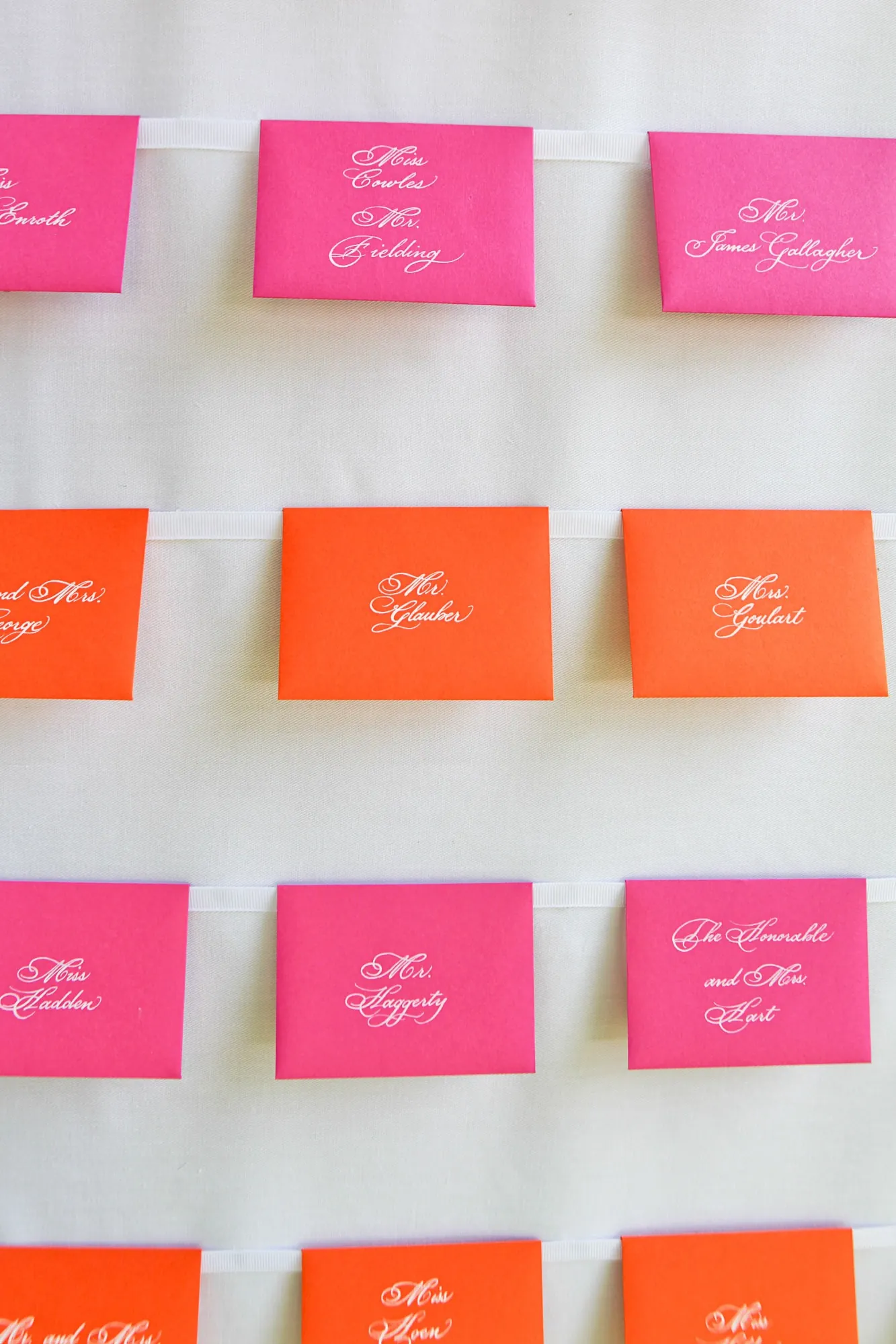 Hot pink and orange escort cards lined up in neat rows
