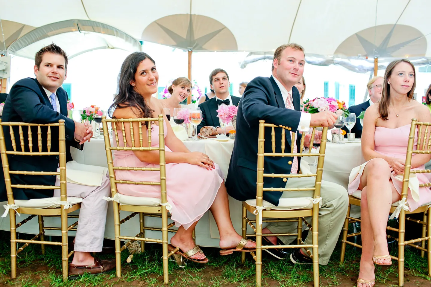 Guests laugh at a table under the tent as parasols hang overhead