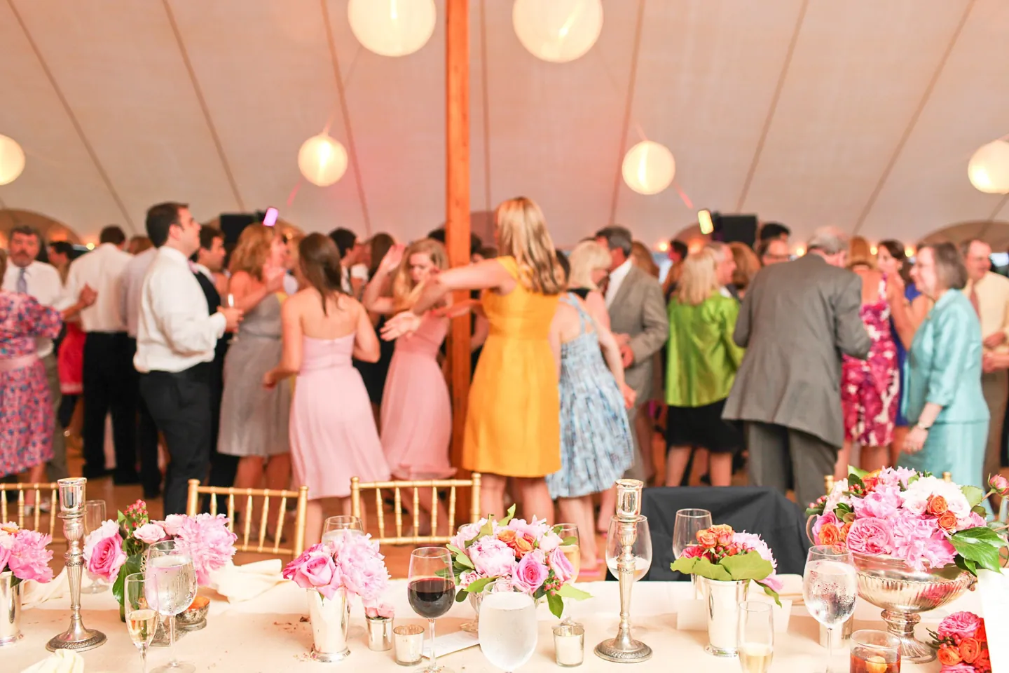 Guests in bright dresses pack the dance floor under paper lanterns