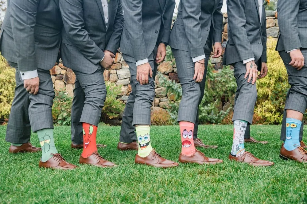 Row of groomsmen's legs in gray plaid trousers showing colorful novelty socks